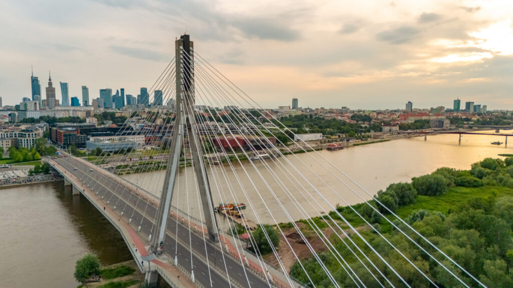 Schrägseilbrücke über die Weichsel mit Warschauer Skyline und Kulturpalast bei Abendlicht.