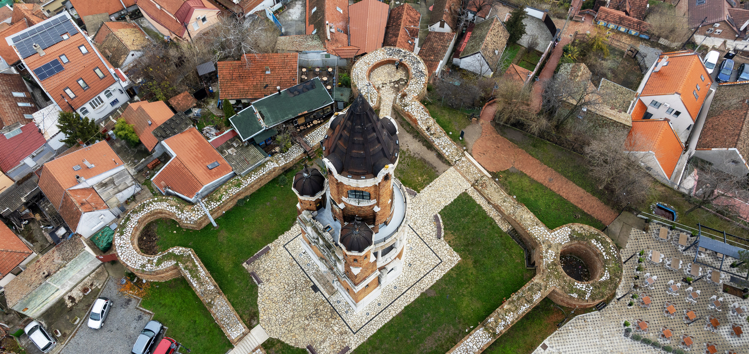 Belgrad, Luftaufnahme des Gardoš-Turms in Zemun, Backsteinturm mit dunklem Kegeldach, von Mauern mit runden Bastionen umgeben, dichtes Viertel mit roten Ziegeldächern