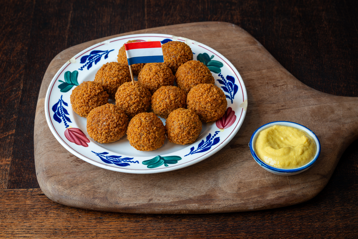 Niederländische Bitterballen, serviert auf einem Teller mit Senf und niederländischer Flagge als Dekoration.