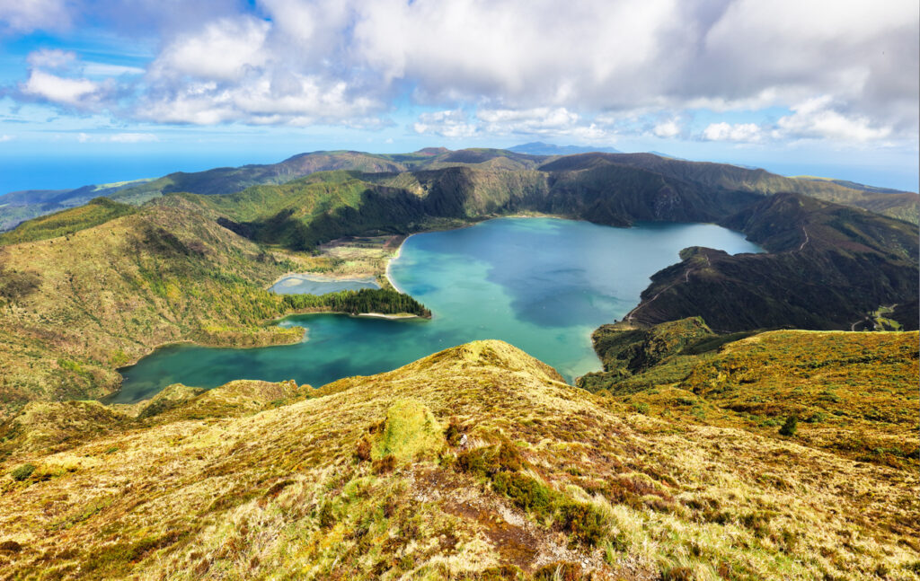 Panoramablick auf die Lagoa do Fogo, einen türkisfarbenen Kratersee auf São Miguel, umgeben von grünen Vulkanhängen und Wolken