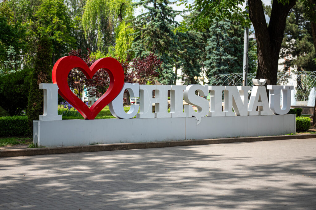 Weißes „I ♥ CHIŞINĂU“-Stadtlogo mit rotem Herz in einem grünen Park, umgeben von Bäumen und Wegen.