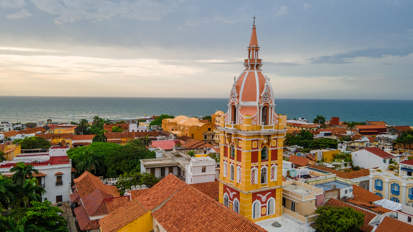 Bunter Kathedralturm über den Dächern Cartagenas mit Blick auf das Karibische Meer.