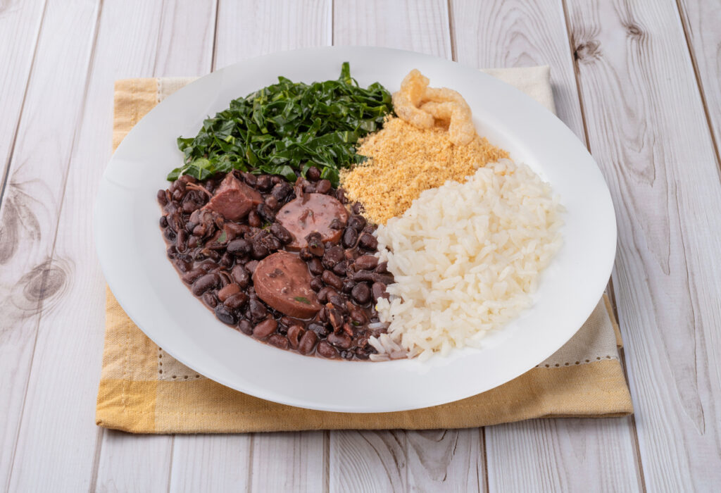 Teller mit Feijoada: schwarze Bohnen mit Fleisch/Wurst, Reis, Farofa, Couve und Schweinekruste.