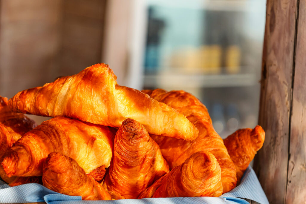 Frisch gebackene goldbraune Croissants in einer Auslage, knusprig und buttrig geschichtet.