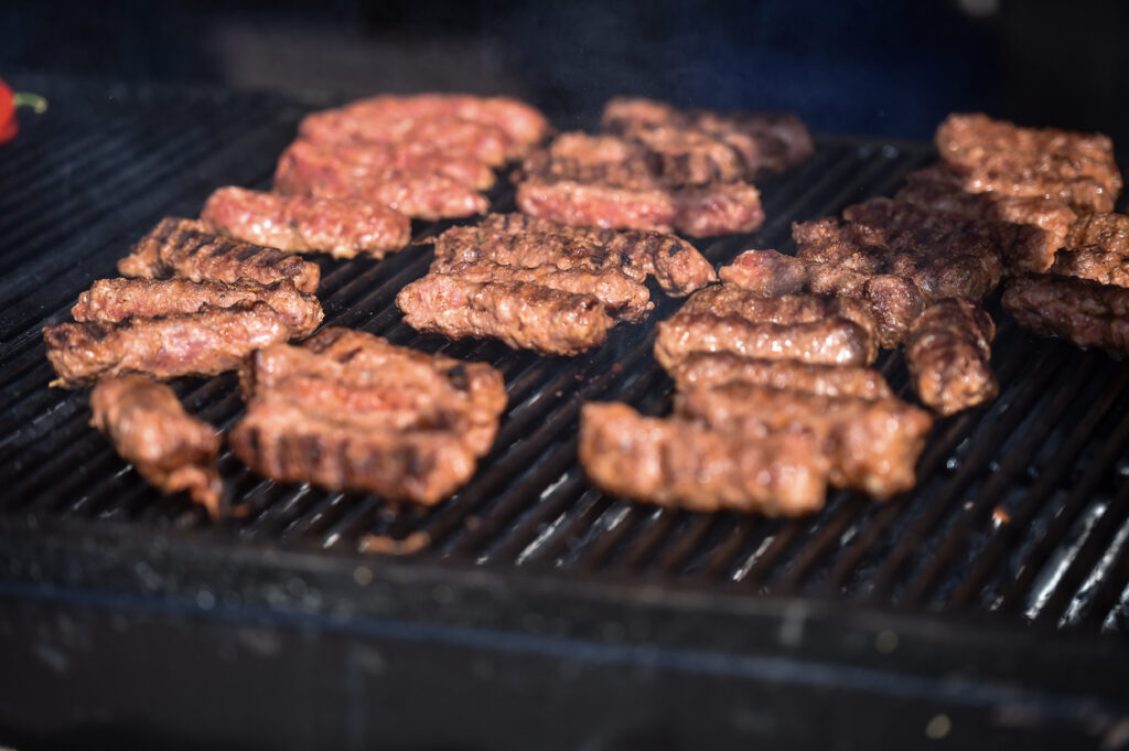 Traditionelle rumänische Mici (gegrillte Hackfleischröllchen) brutzeln auf einem Holzkohlegrill.