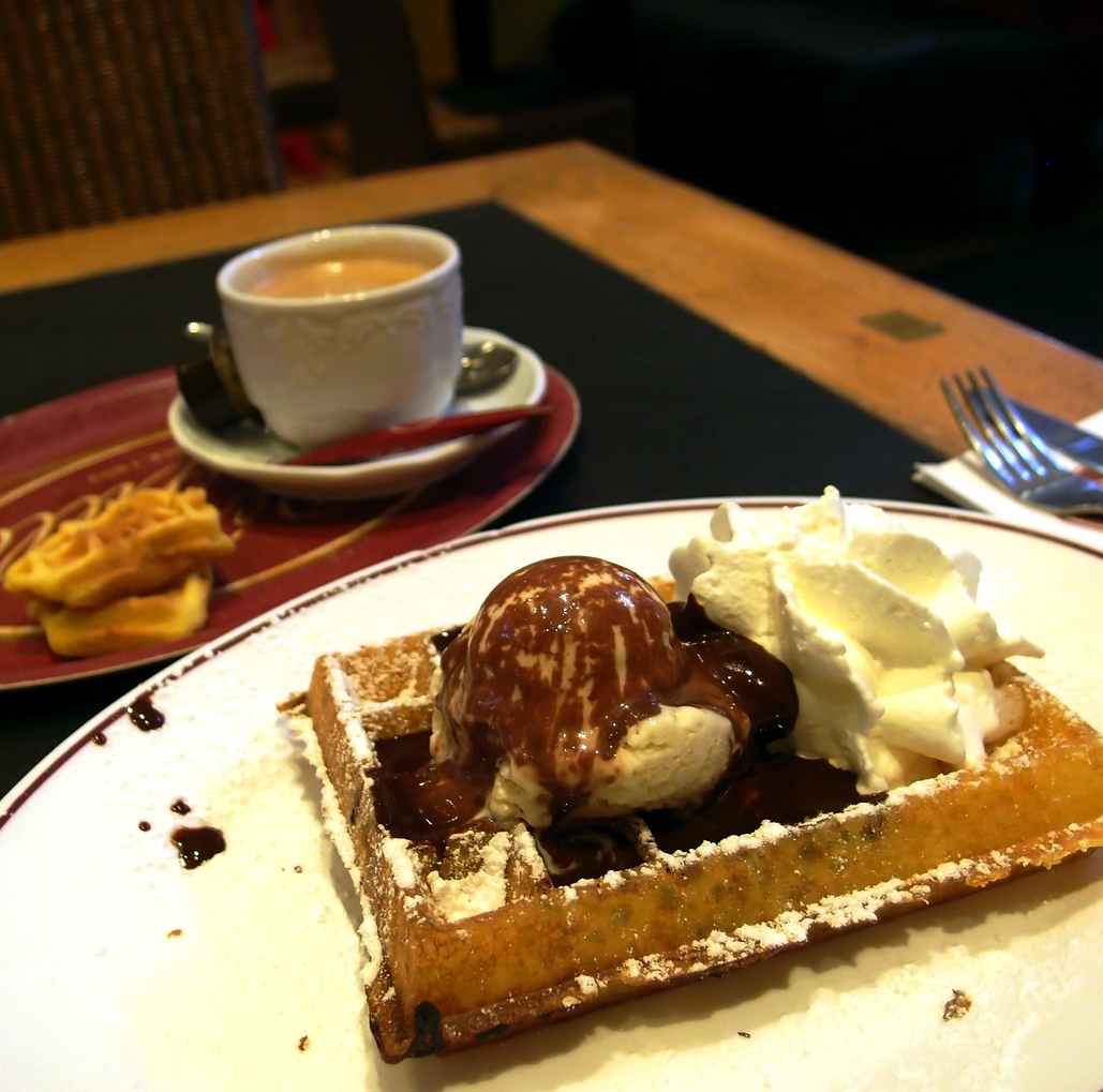 Belgische Waffel mit Eis, Schokolade und Sahne neben Kaffee in Antwerpen