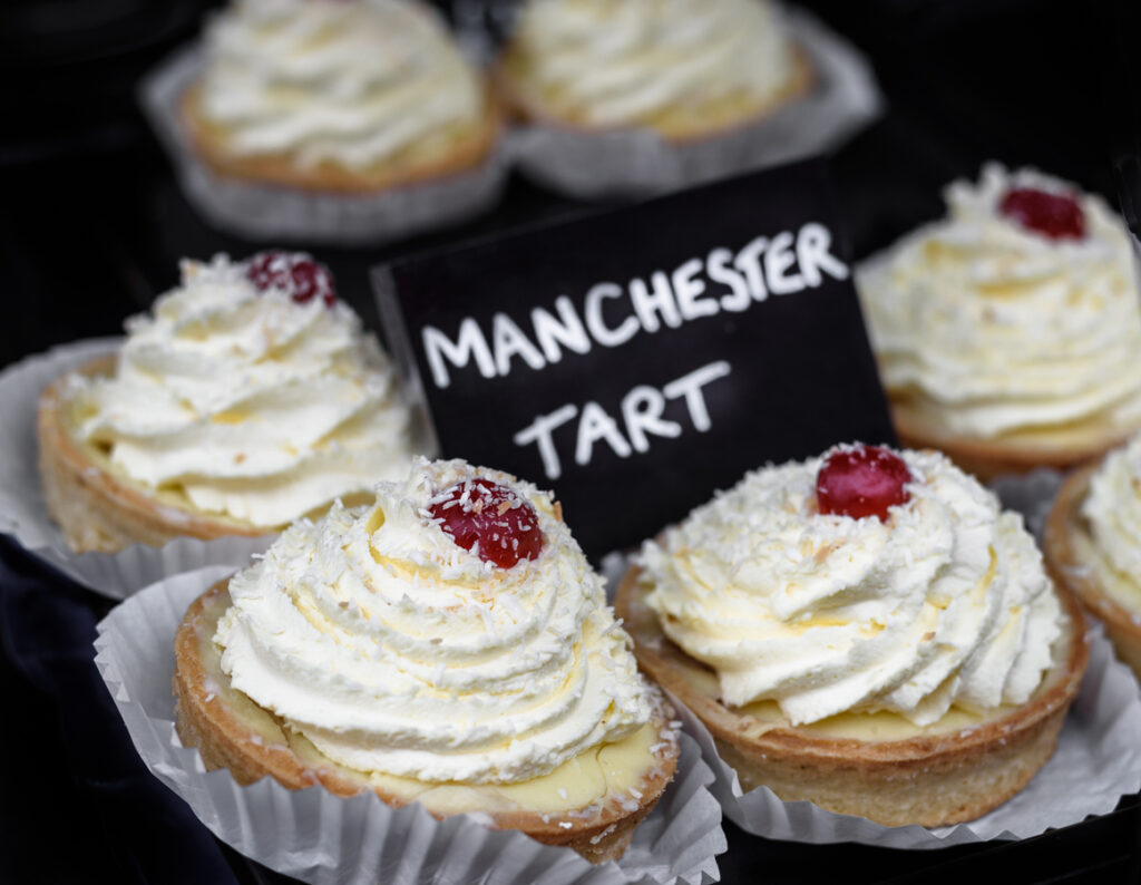 Manchester Tarts mit Vanillecreme, Kokos und Kirsche im Bäckerei-Display