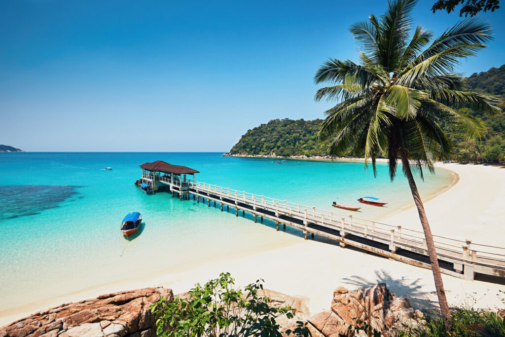 Weißer Sandstrand mit Steg und Pavillon auf den Perhentian-Inseln, türkisblaues Meer und Palmen