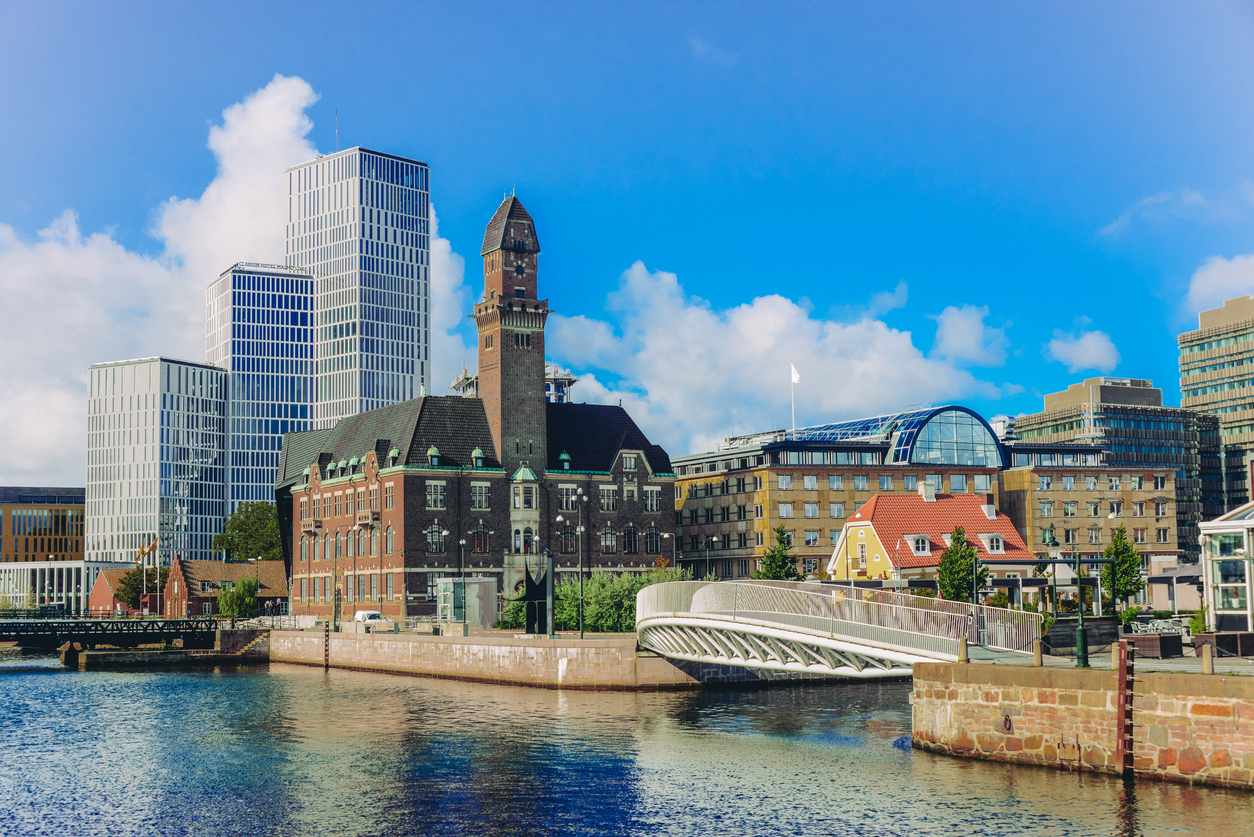 Blick auf die Skyline von Malmö mit modernen Hochhäusern, historischem Rathaus und Brücke am Wasser.