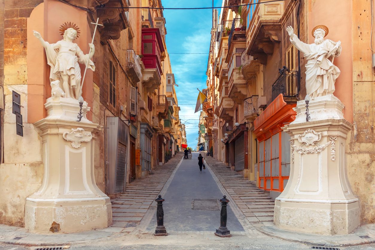 Zwei Heiligenstatuen am Eingang einer malerischen Gasse mit typischen Balkonen in Valletta, Malta.