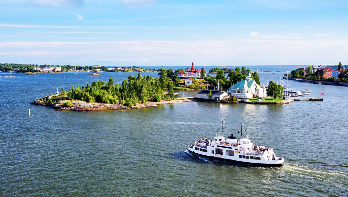 Fähre fährt durch die Schären vor Helsinki mit kleinen Inseln und historischen Gebäuden.