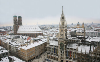 Panoramablick auf den Marienplatz in München mit Frauenkirche und Rathaus im Schnee.