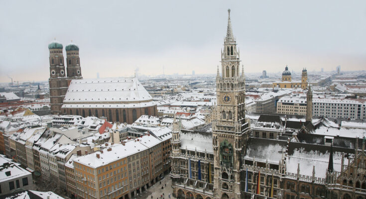 Panoramablick auf den Marienplatz in München mit Frauenkirche und Rathaus im Schnee.