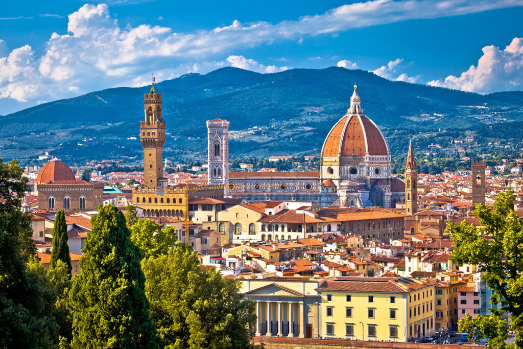 Panorama von Florenz mit der Kathedrale Santa Maria del Fiore, Giottos Campanile und dem Palazzo Vecchio vor grünen Hügeln.