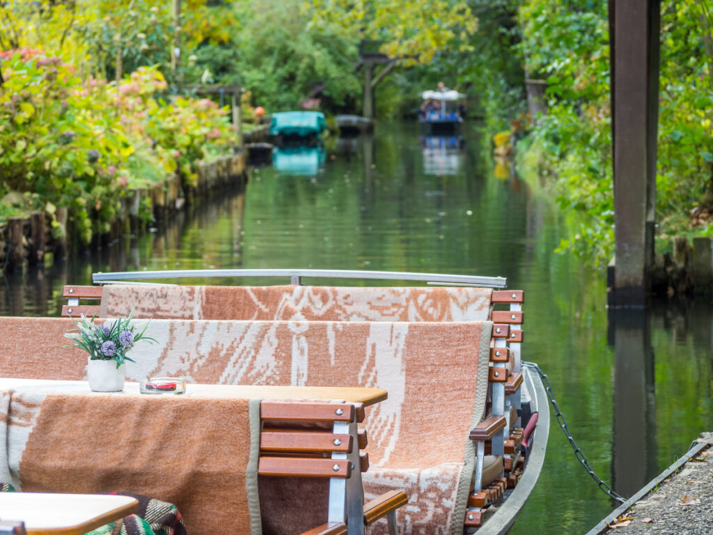 Ein Holzkahn mit Wolldecken liegt am ruhigen Fließ in Lübbenau.