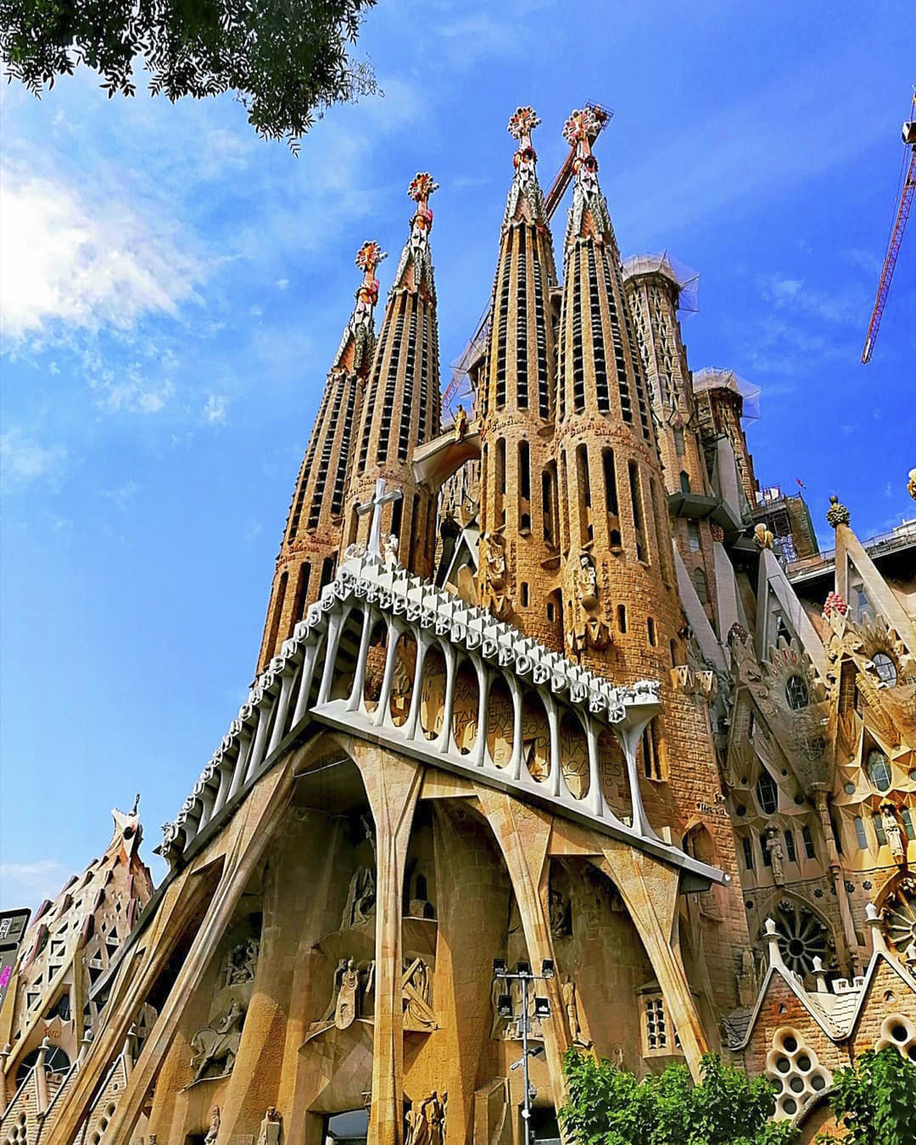 Nahaufnahme der Sagrada Família in Barcelona mit detailreicher Fassade und hohen Türmen, flankiert von Baukränen.