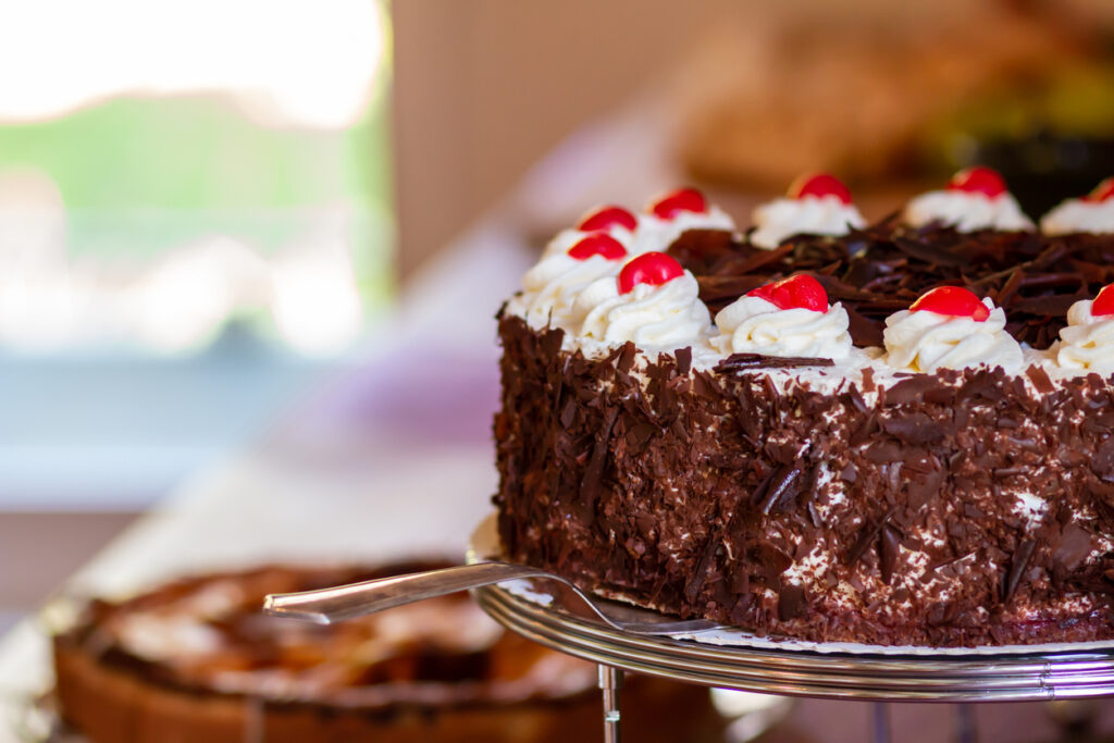 Nahaufnahme einer Schwarzwälder Kirschtorte mit Sahnetuffs, Kirschen und Schokoraspeln.