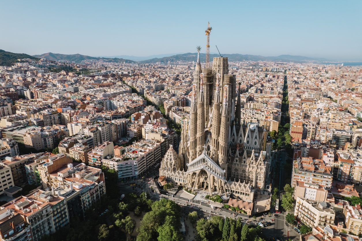 Luftaufnahme der Sagrada Família mit Baukränen, umgeben von symmetrischen Straßenblöcken.