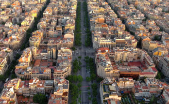 Von oben sieht man die baumbestandene Mittelachse des Passeig de Gràcia, flankiert von Eixample-Blocks mit Innenhöfen und Kreuzungen im Schachbrettmuster.