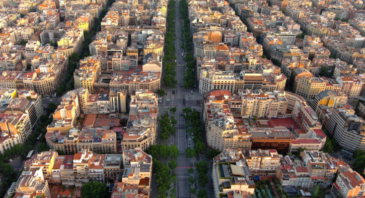 Von oben sieht man die baumbestandene Mittelachse des Passeig de Gràcia, flankiert von Eixample-Blocks mit Innenhöfen und Kreuzungen im Schachbrettmuster.