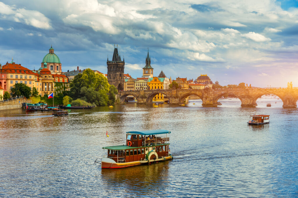 Historische Karlsbrücke mit Booten auf der Moldau und Prager Altstadt im Hintergrund.