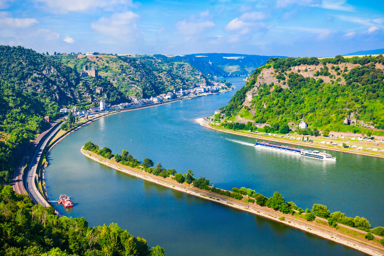 Luftaufnahme der Rheinschleife an der Loreley bei St. Goarshausen mit steilen Felsen, Uferstraße und Flusskreuzfahrtschiff.