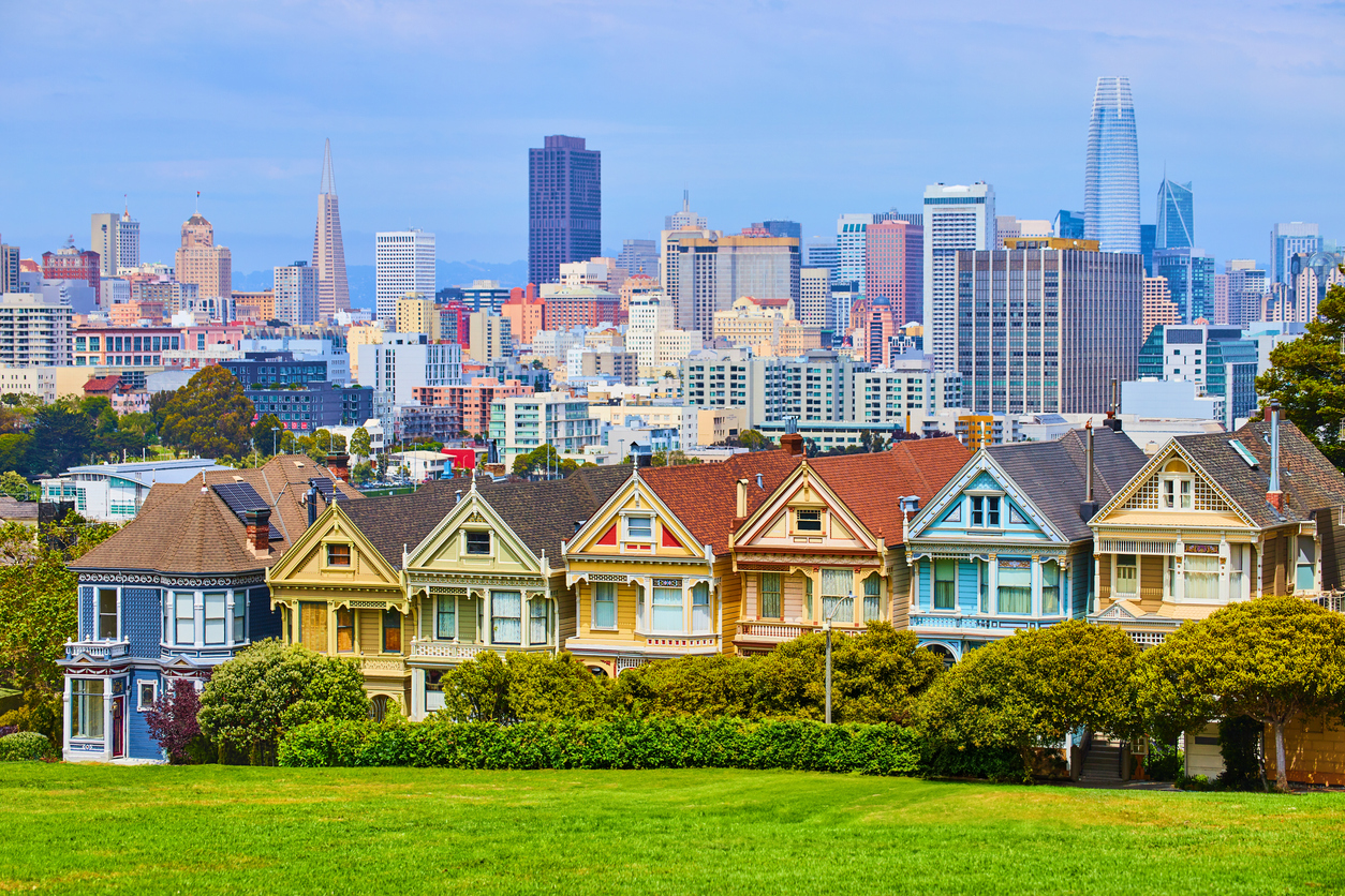 Farbige viktorianische Painted-Ladies-Häuser am Alamo Square in San Francisco mit Downtown-Skyline im Hintergrund.
