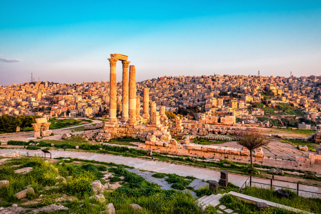Antike Säulen des Herkulestempels überblicken die dicht bebaute Stadt Amman im warmen Abendlicht.