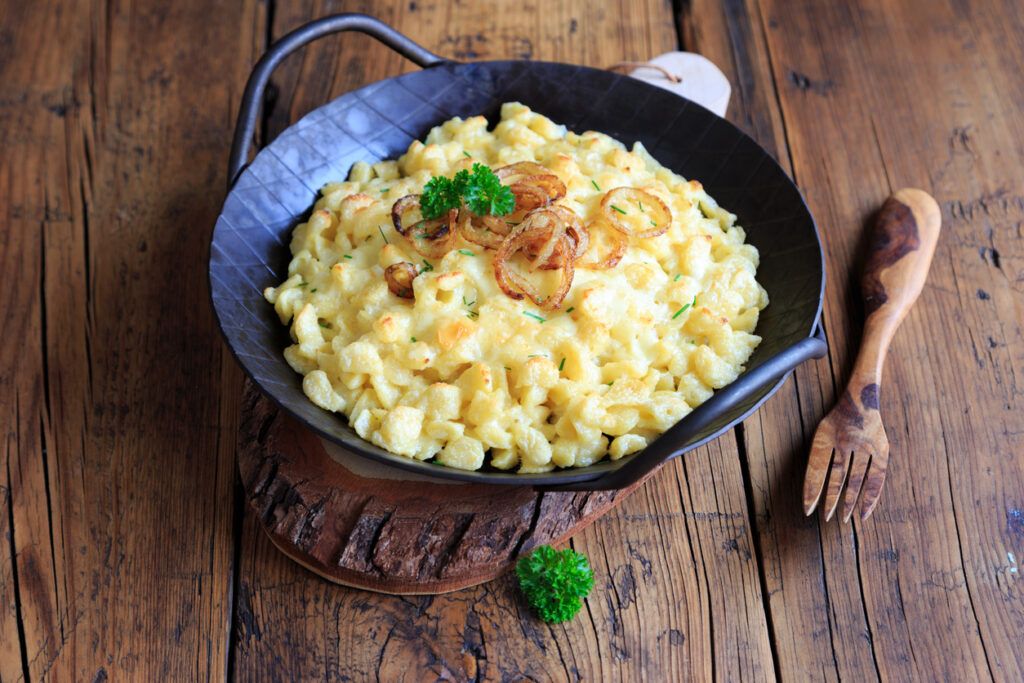 Rustikale Pfanne mit Käsespätzle, karamellisierten Zwiebeln und etwas Petersilie.