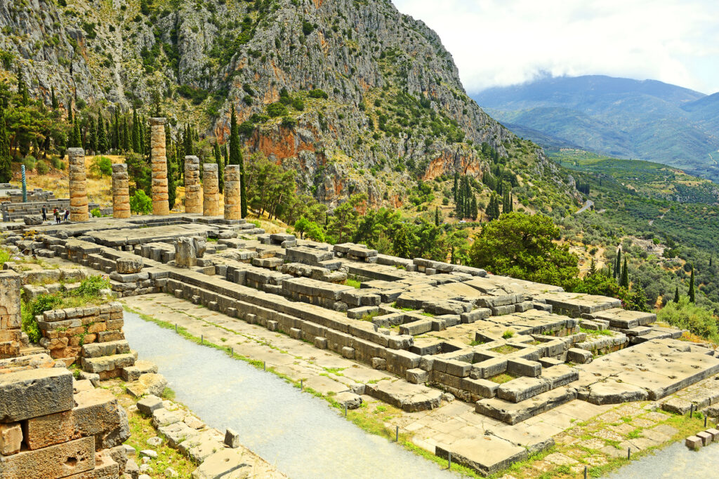 Ruinen des Apollon-Tempels in Delphi mit wenigen Säulen am terrassierten Berghang.