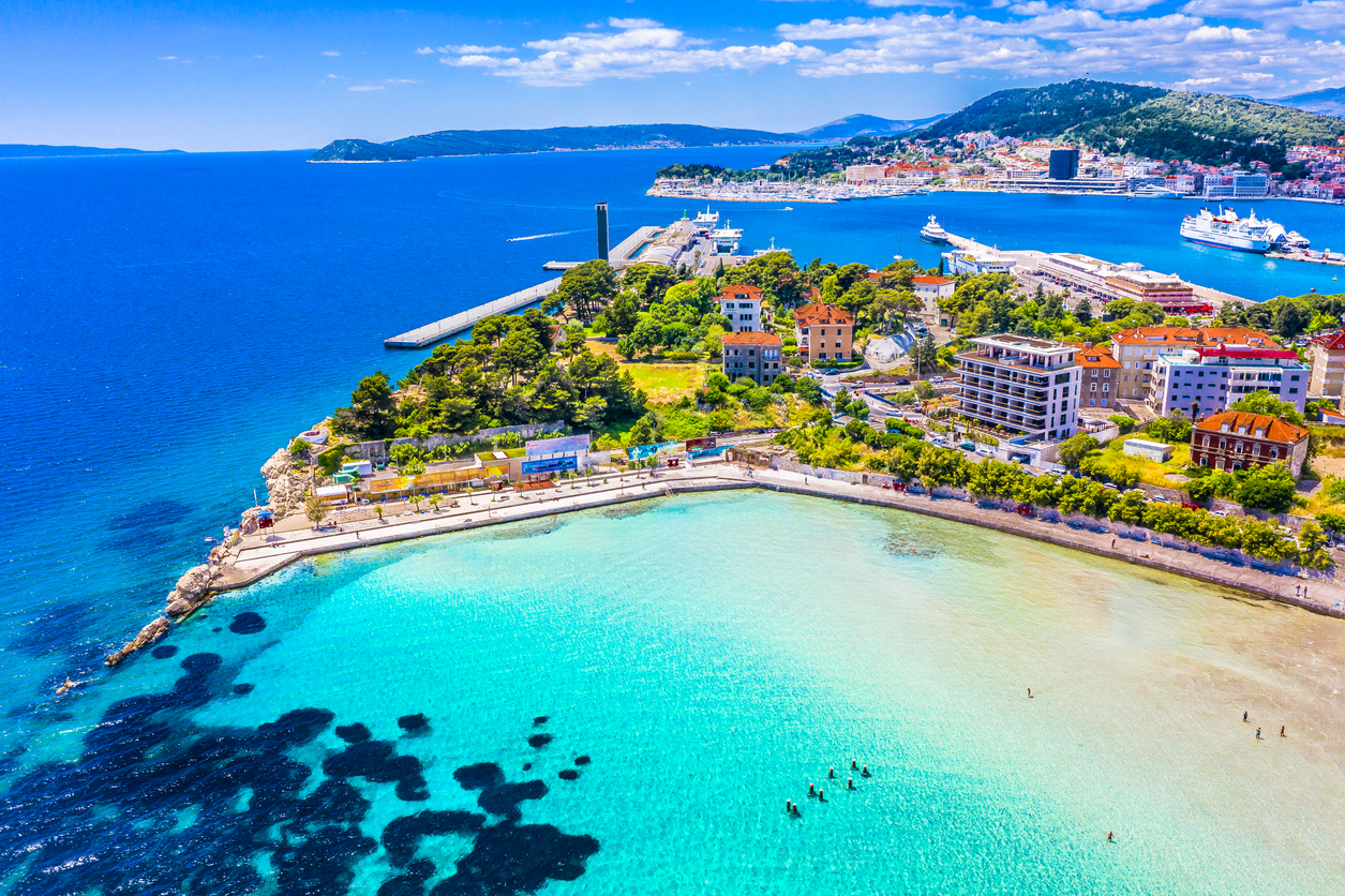 Luftaufnahme der Küste von Split mit türkisfarbenem Wasser, Promenade und Fährhafen.