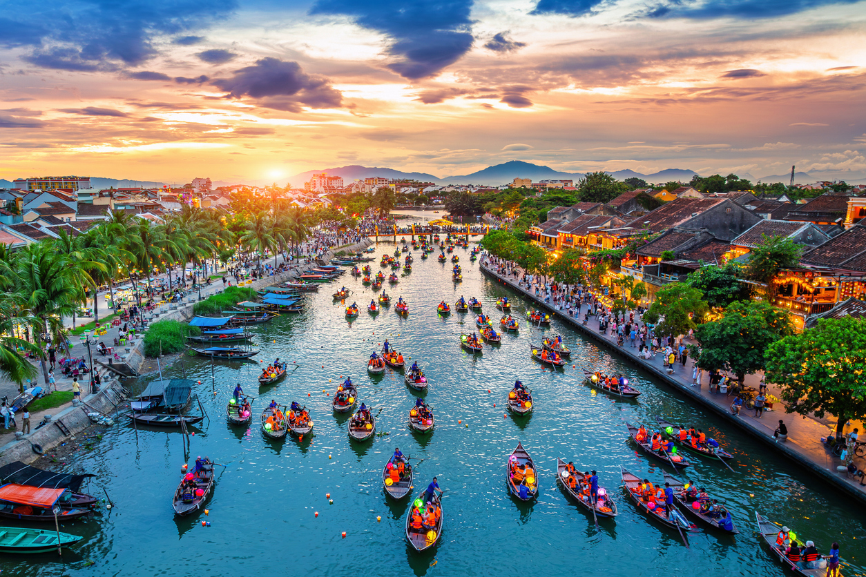 Bunte Laternenboote auf dem Thu-Bon-Fluss vor der beleuchteten Altstadt von Hoi An.