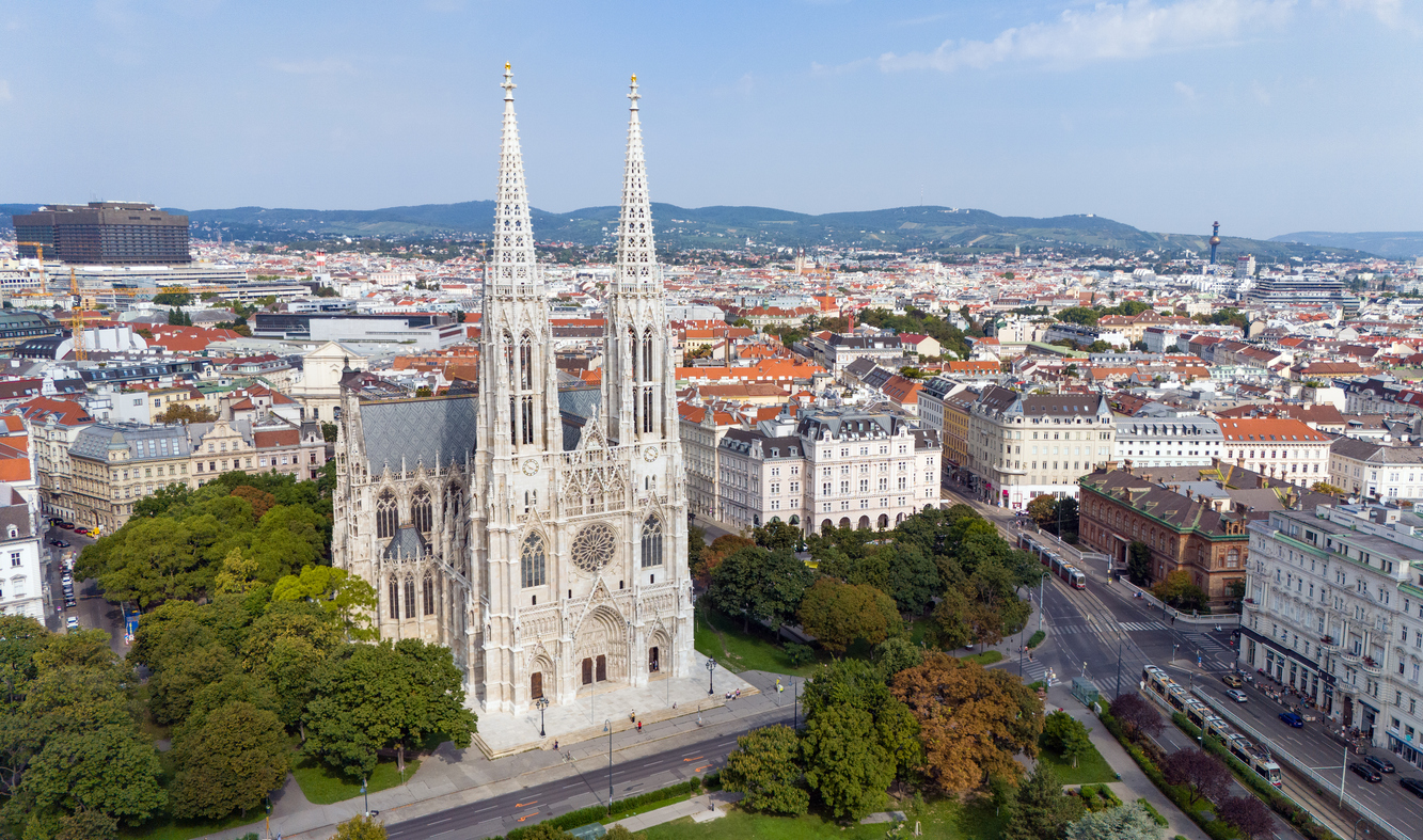 Luftaufnahme der neugotischen Votivkirche mit Doppeltürmen und Park in Wien.
