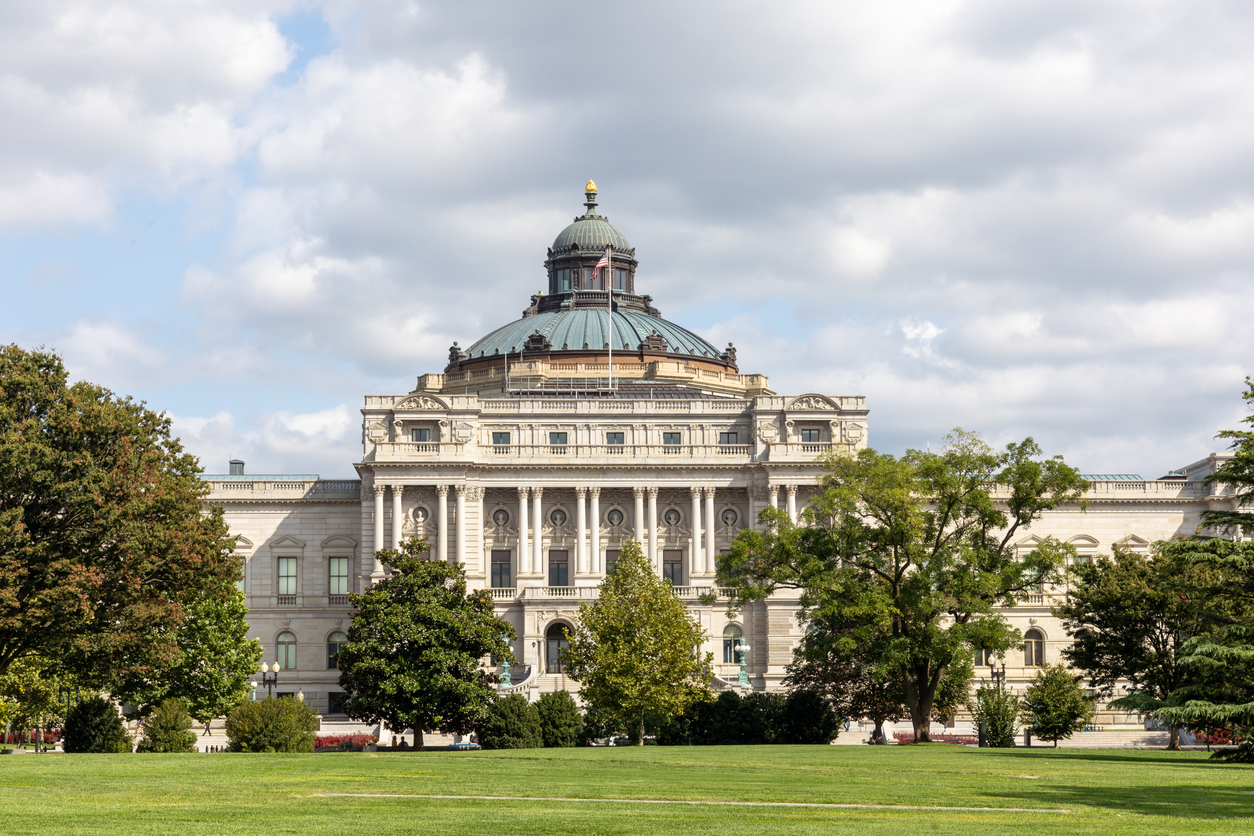 Frontansicht der Library of Congress (Thomas-Jefferson-Building) in Washington, D.C. mit kupferner Kuppel, Säulenfassade, Rasen und Bäumen bei Tageslicht.