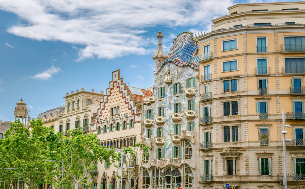 Die Jugendstilfassade der Casa Batlló mit schuppigem Dach und knochenartigen Balkonen steht zwischen der Casa Amatller und einem klassischen Eixample-Haus am Passeig de Gràcia.