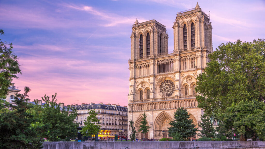 Vorderfassade der Kathedrale Notre-Dame in Paris vor rosa Abendhimmel.