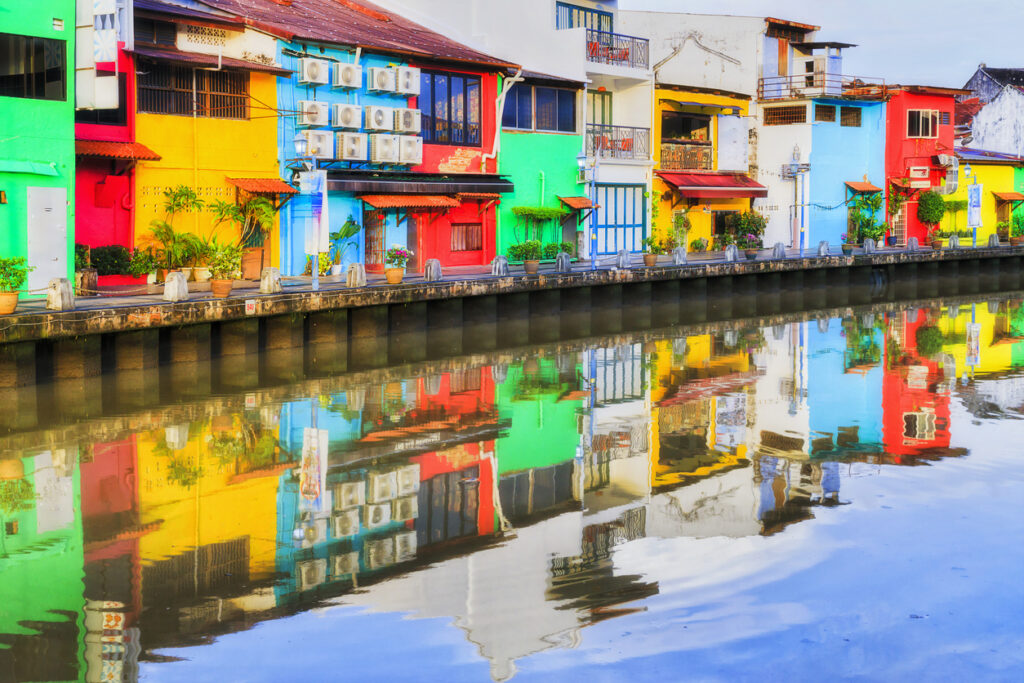 Farbige Fassaden spiegeln sich im ruhigen Malacca-Fluss.
