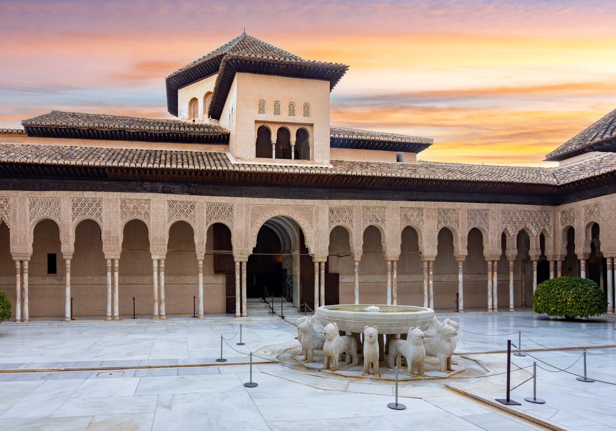 Marmorhof mit Löwenbrunnen, Arkaden und filigranen maurischen Stuckarbeiten in der Alhambra Granada bei Sonnenuntergang.