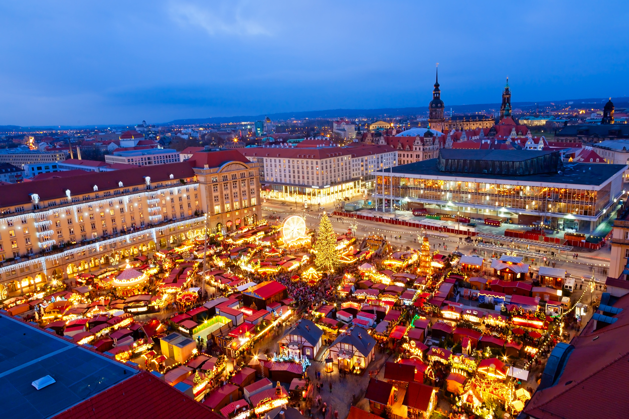 Luftaufnahme des Dresdner Weihnachtsmarkts am Altmarkt mit Baum, Buden und Riesenrad in der Dämmerung.