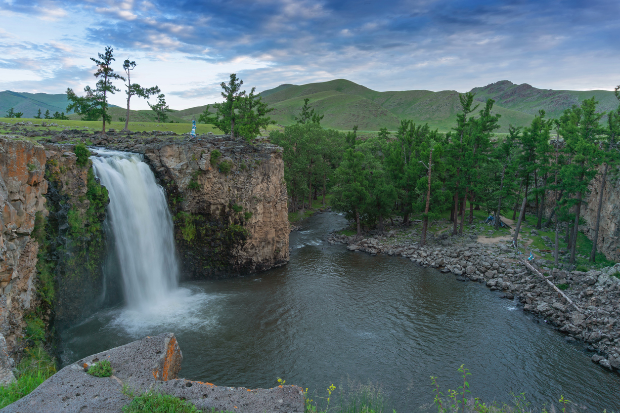 Wasserfall mit Felskante, Kiefern und sanften Hügeln im Orkhon-Tal.