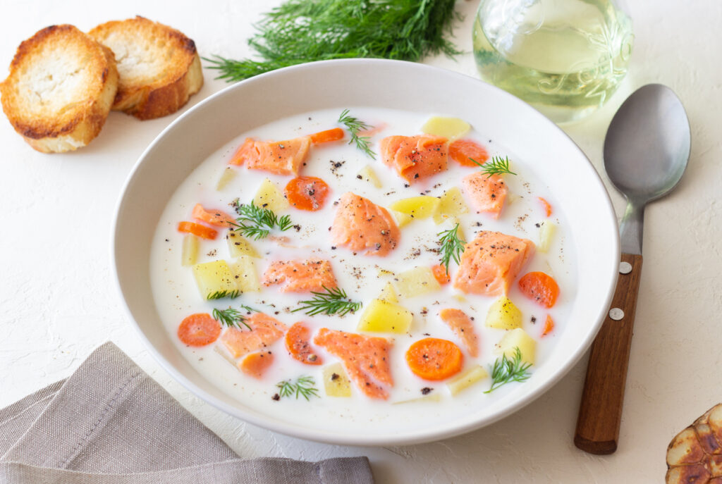 Cremige Suppe mit Lachs, Kartoffeln, Karotten und Dill in einer Schüssel.