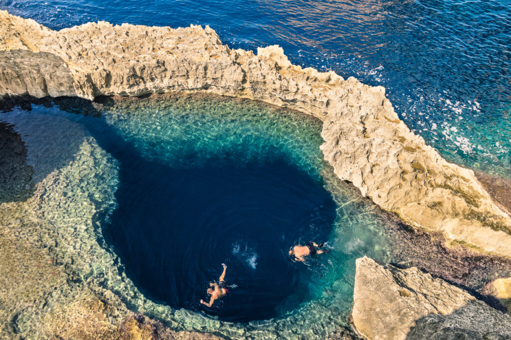 Natürliches Blue Hole auf Gozo mit zwei Schnorchlern im tiefblauen Pool.