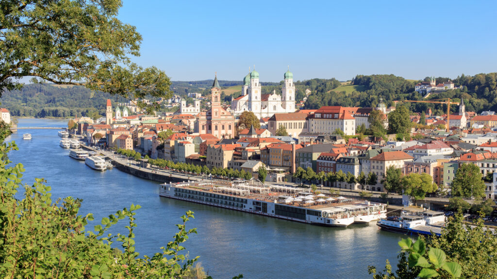 Panorama von Passau mit Dom St. Stephan an der Donau und mehreren Flusskreuzfahrtschiffen.