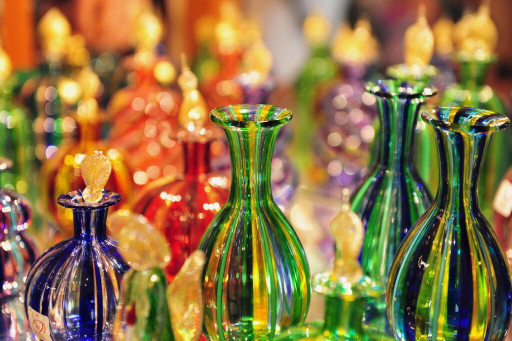 Nahaufnahme farbenfroher, handgefertigter Murano-Glasvasen mit goldenen Stopfen in einer Glaswerkstatt auf der Insel Murano bei Venedig.