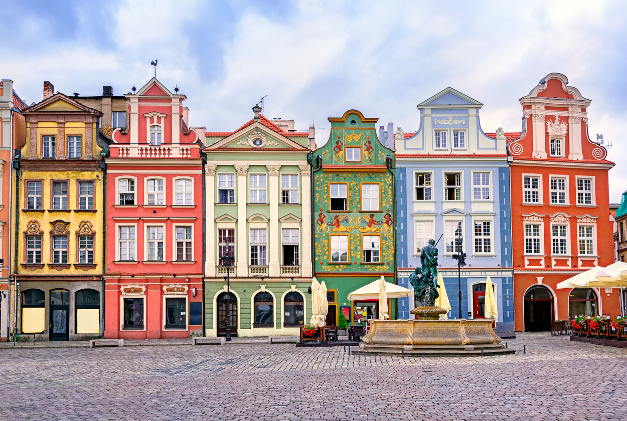 Bunte Fassaden am Stary Rynek mit Brunnen im Vordergrund.