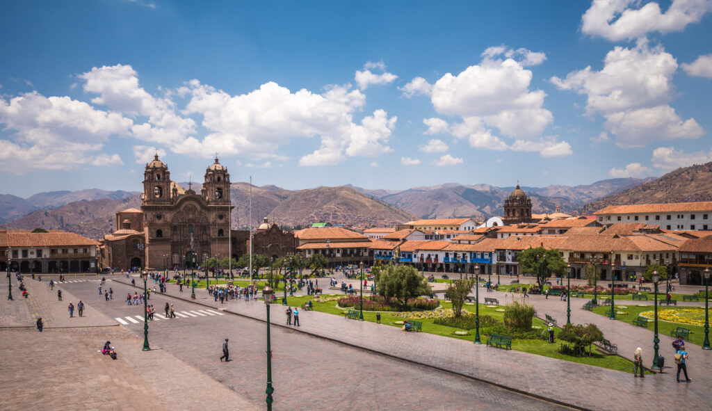 Weitblick auf die Plaza de Armas in Cusco mit Kirchen, Kolonialfassaden und Bergen dahinter.