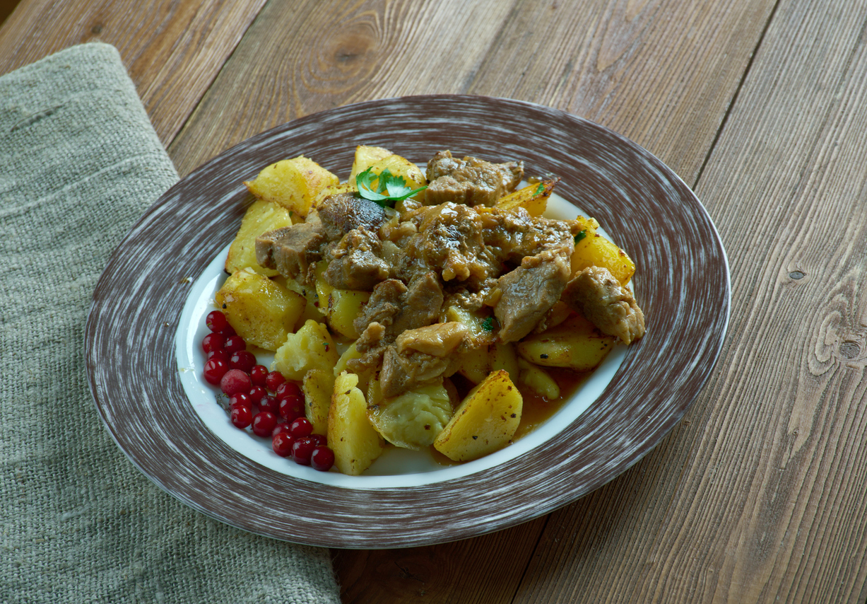 Teller mit Poronkäristys aus sautiertem Rentierfleisch auf Bratkartoffeln, garniert mit Preiselbeeren.