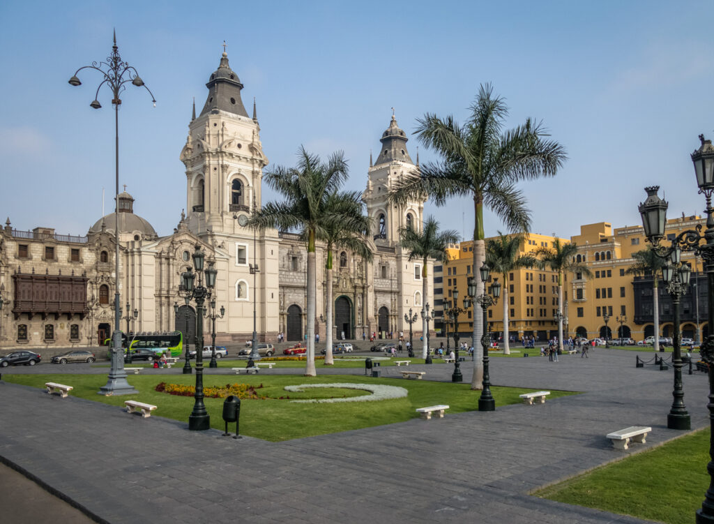 Der Plaza Mayor zeigt die Kathedrale von Lima mit Palmen und historischen Gebäuden.