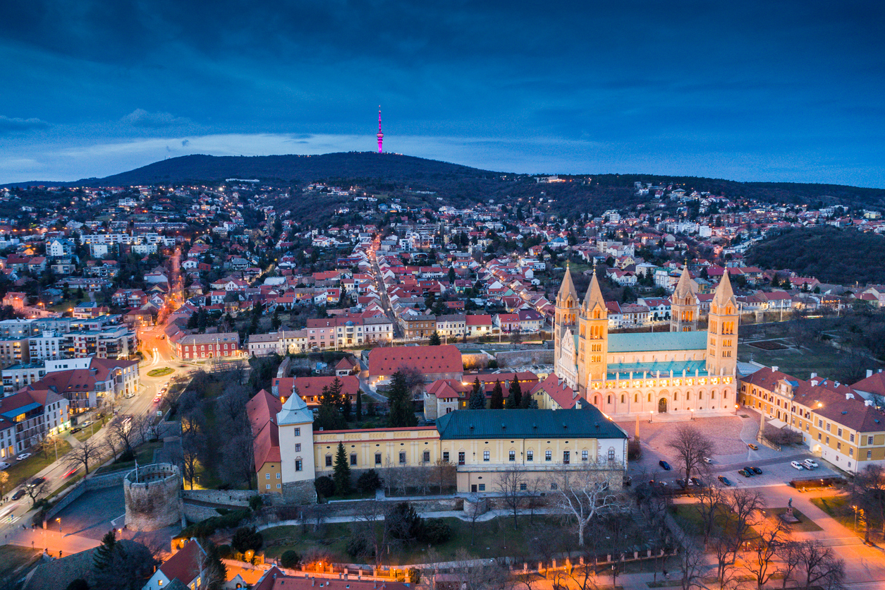 Luftaufnahme von Pécs mit beleuchtetem Dom und TV-Turm am Mecsek.
