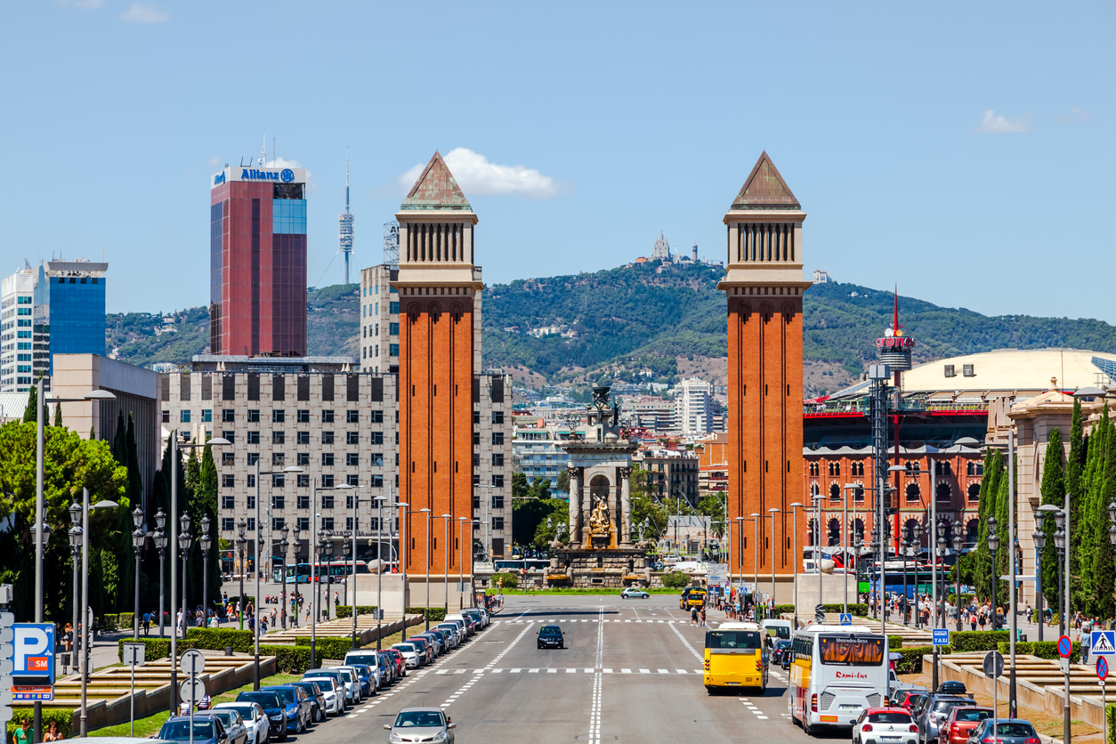 Vom Montjuïc aus sieht man die beiden Venezianischen Türme, die Avinguda de la Reina Maria Cristina und dahinter den Tibidabo unter blauem Himmel.